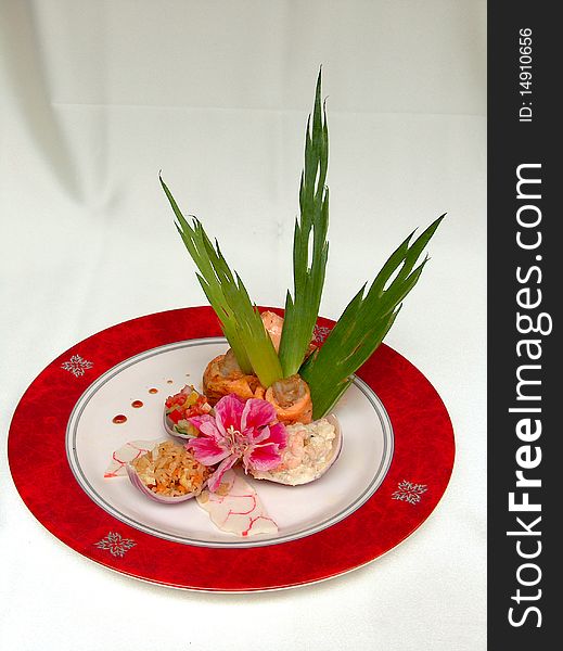 The fillet barracuda decorated salmon, green leaves and flower on the round plate with red border. The fillet barracuda decorated salmon, green leaves and flower on the round plate with red border.