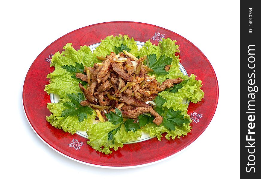 Green leaves of lettuce on the red plate. On lettuce leaves are lying pieces of beef and pork meat fried with an onions with addition of an apple and a gherkin, filled with mayonnaise. Green leaves of lettuce on the red plate. On lettuce leaves are lying pieces of beef and pork meat fried with an onions with addition of an apple and a gherkin, filled with mayonnaise.