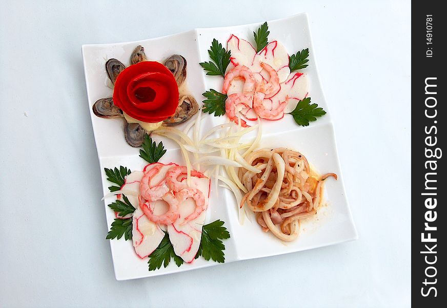 The white square plate of calamar, shrimps, crab meat, mussels, tomato, mayonnaise. The white square plate of calamar, shrimps, crab meat, mussels, tomato, mayonnaise.