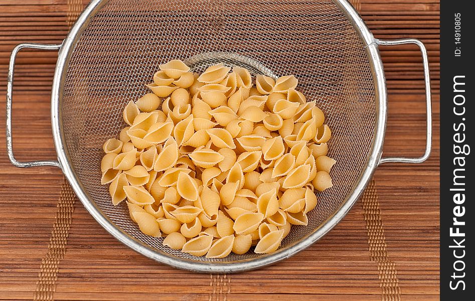 Dry Pasta in Strainer on Bamboo Mat