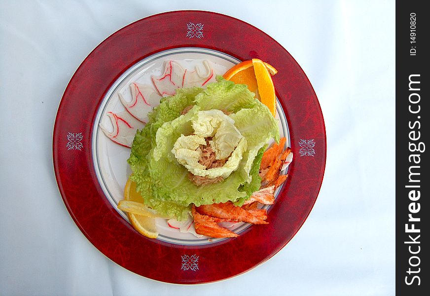 The red plate of Tunas salad. Components: the Chinese salad, crab meat, shrimps, an apple, a dark blue onions, a tuna and mayonnaise.