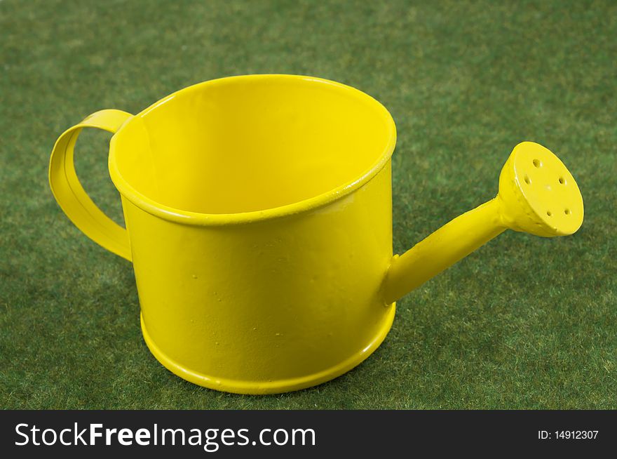 Yellow watering can on a green grass carpet