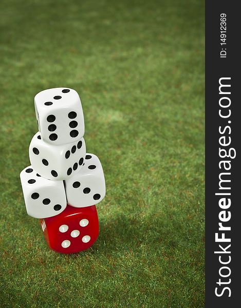 Piled dice on a red one over a green carpet