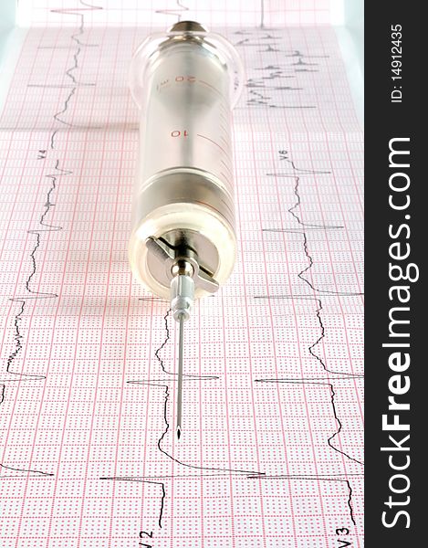 Old glass syringe on the cardiogram tape