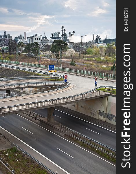 Empty highway with traffic signs in morning light and chemical plant in background. Empty highway with traffic signs in morning light and chemical plant in background