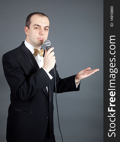 Man in tuxedo talks into microphone. Man in tuxedo talks into microphone