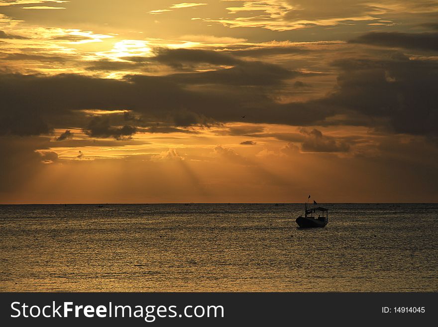 Golden sunset at sea with silhouette of a boat. Golden sunset at sea with silhouette of a boat