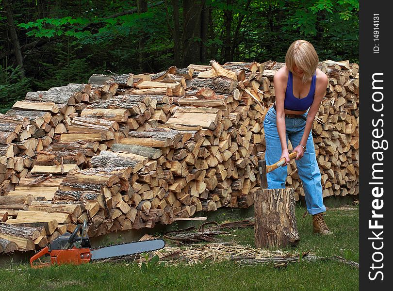 women lumberjack cutting firewood in front of woodpile. women lumberjack cutting firewood in front of woodpile