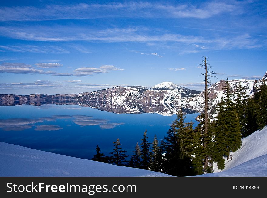 Landscape view of beautiful Crater Lake in the Springs months with snow in the rim walk. Landscape view of beautiful Crater Lake in the Springs months with snow in the rim walk