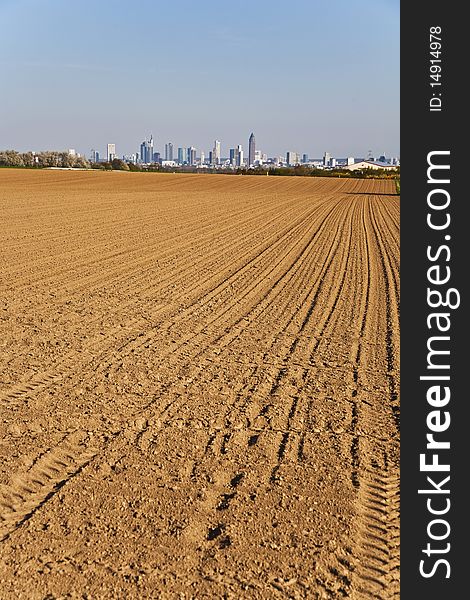 Freshly ploughed acre with skyline of Frankfurt at the horizon