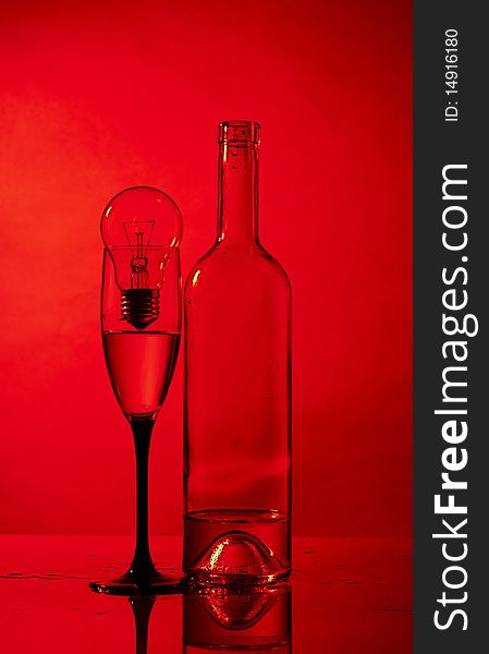 Bottle, glass and bulb on red background