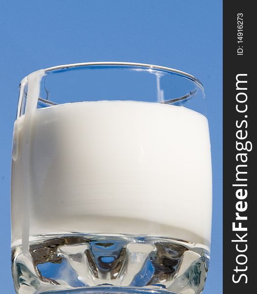 Glass from transparent glass with milk on a blue background. Glass from transparent glass with milk on a blue background