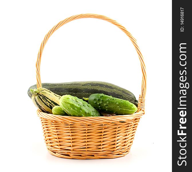 Squash and cucumbers in a basket on a white ground