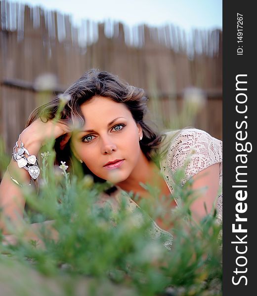 Young pretty summer woman lying on the grass and smiling