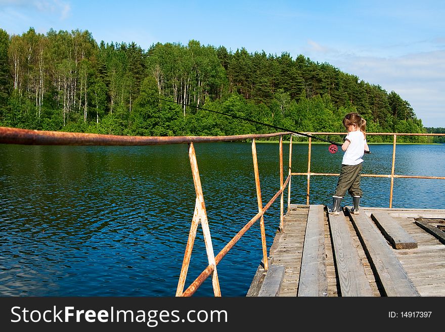 Little beautifull girl fishing. She stays on old pier with long rod. Little beautifull girl fishing. She stays on old pier with long rod.