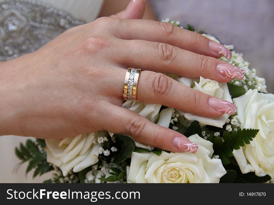 The hand of the bride lies on a wedding bouquet