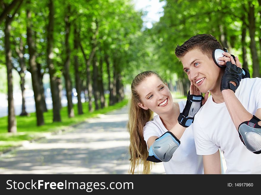The young guy with the girl in park listens to music. The young guy with the girl in park listens to music