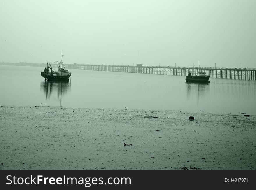 Two boats waiting waves in a foggy day, one bridge in background. Two boats waiting waves in a foggy day, one bridge in background