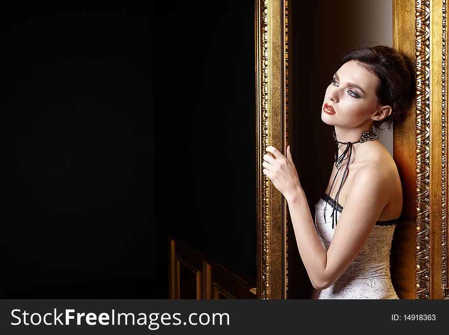 The beautiful girl with a make-up at a gold door