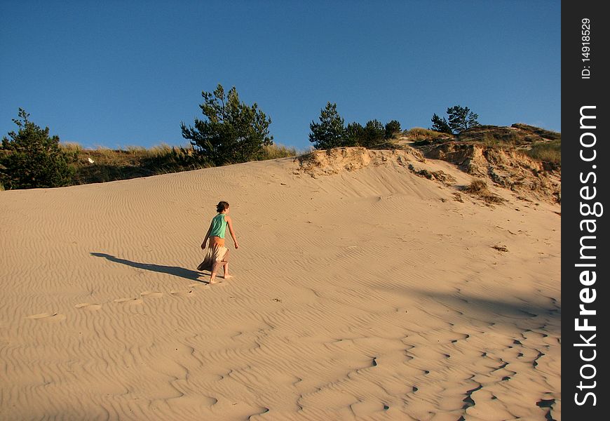 Lonely girl trekking and admiring the sands of the dunes. Lonely girl trekking and admiring the sands of the dunes