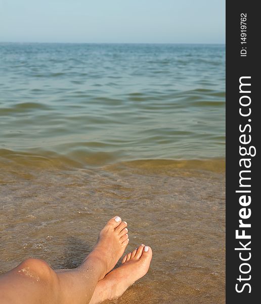 Two womens feet on the calm and sunny, empty beach. Two womens feet on the calm and sunny, empty beach.