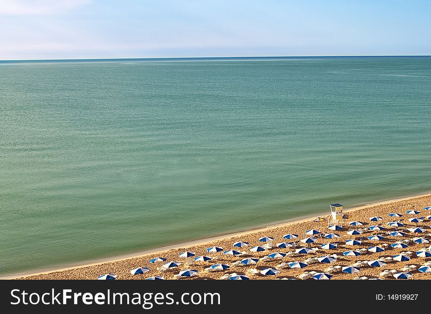 Clean, empty sea coast with umbrellas on the sand. Clean, empty sea coast with umbrellas on the sand.