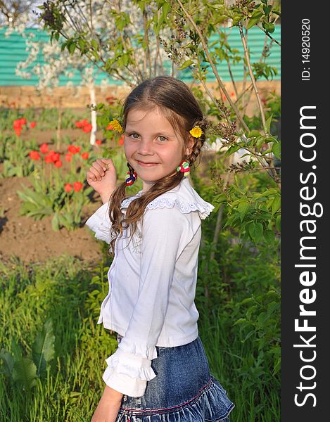 Little girl stands and smiles in the spring garden. Little girl stands and smiles in the spring garden