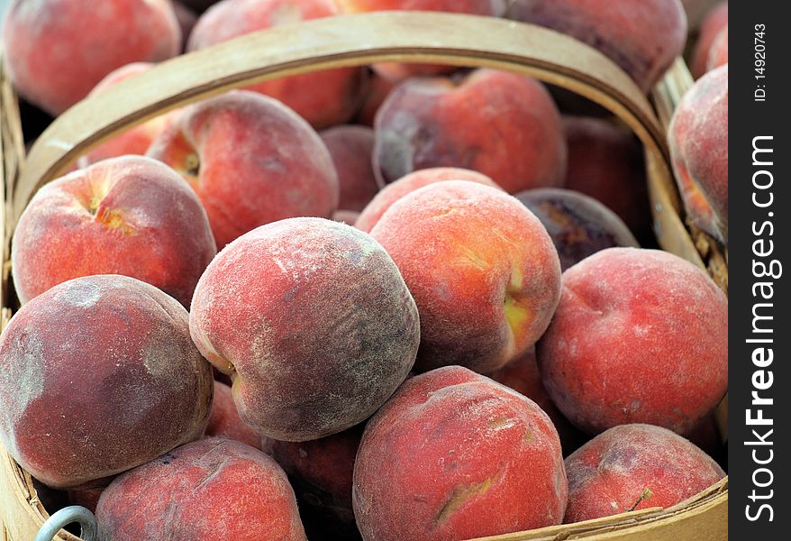 Peaches for sale at the market. In a basket.