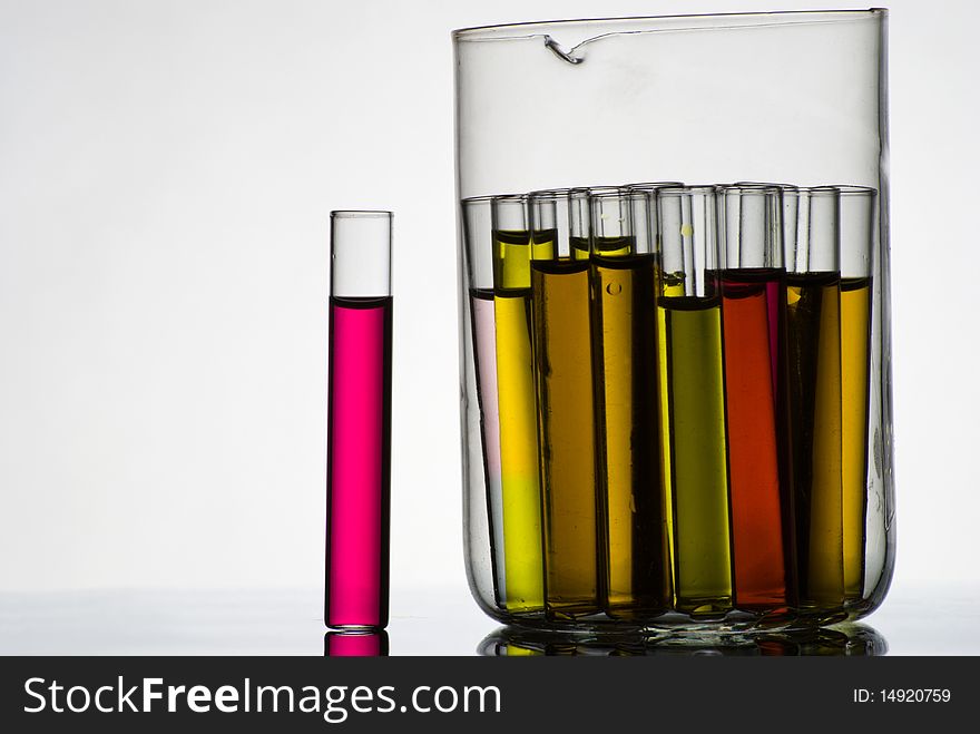 Test tubes filled with colored liquids in glass container on white. Test tubes filled with colored liquids in glass container on white