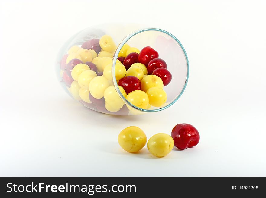 Red and yellow cherries in glass isolated on white