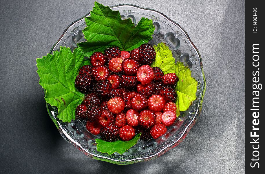 Red and purple raspberries in glass bowl.