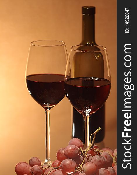 Grapes and two wineglasses near bottle of red wine on brown background. Grapes and two wineglasses near bottle of red wine on brown background