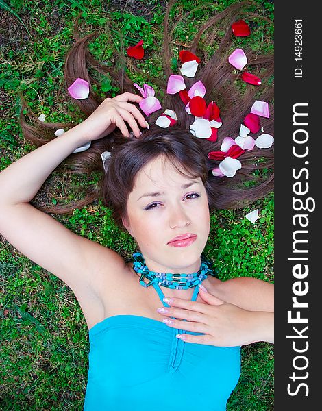 Girl is laying on the grass with petals in hair