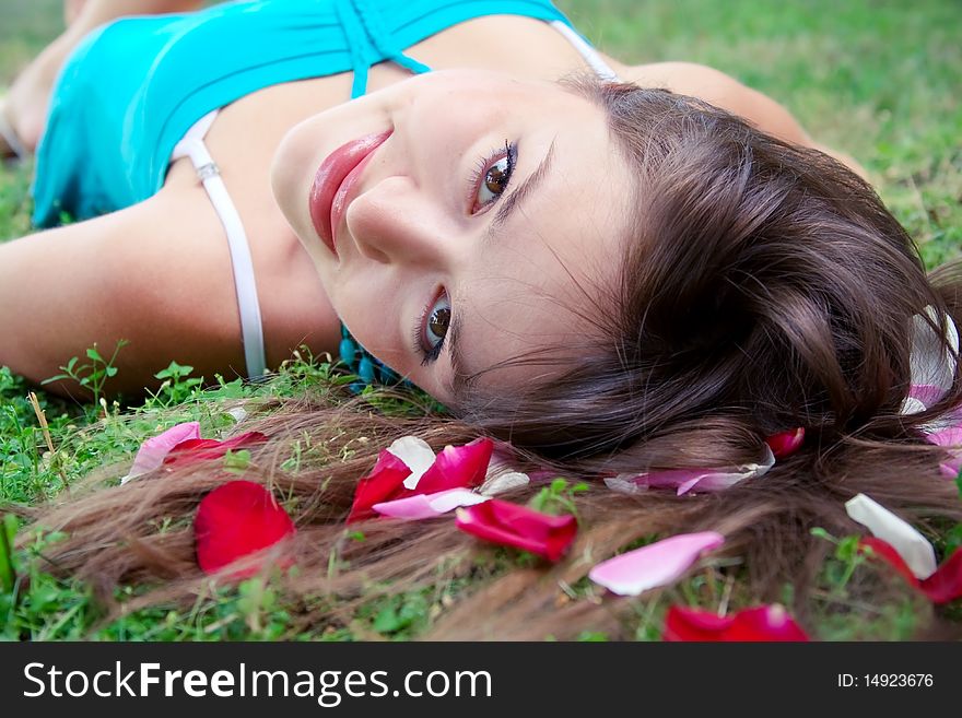 Lying girl and petals of rose in the hair