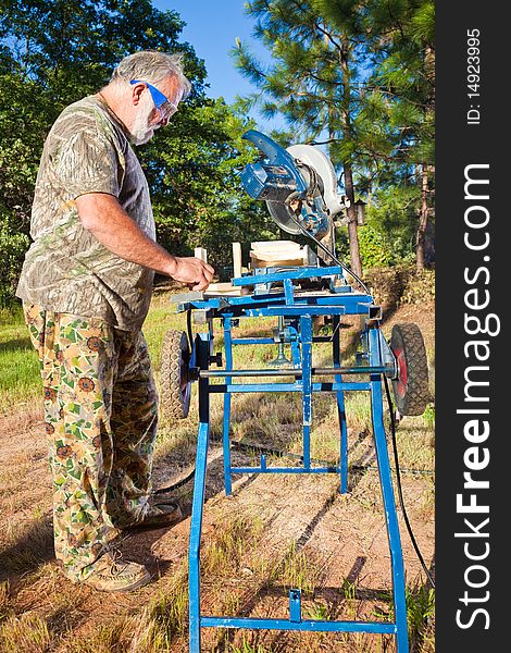 Active older man working with wood in the yard. Active older man working with wood in the yard.