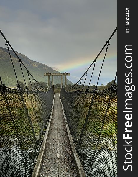 A footbridge leading towards a beautiful rainbow. A footbridge leading towards a beautiful rainbow