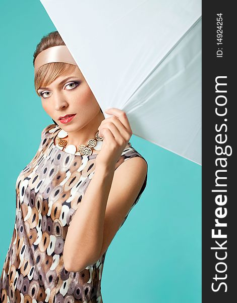 Beautiful fashion girl on the turquoise background with umbrella