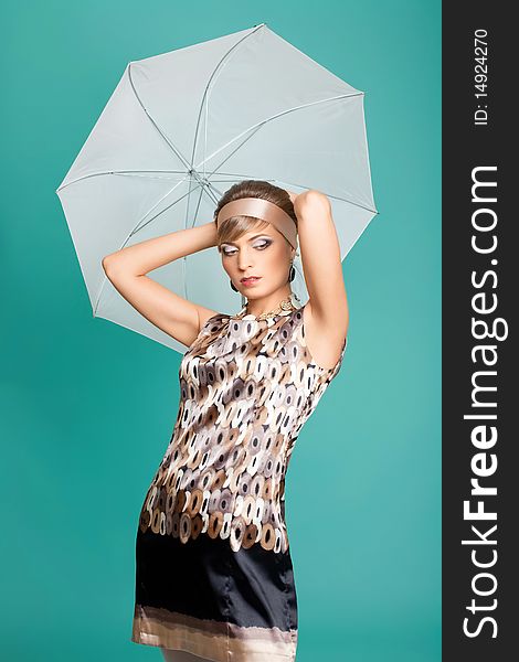 Beautiful fashion girl on the turquoise background with umbrella