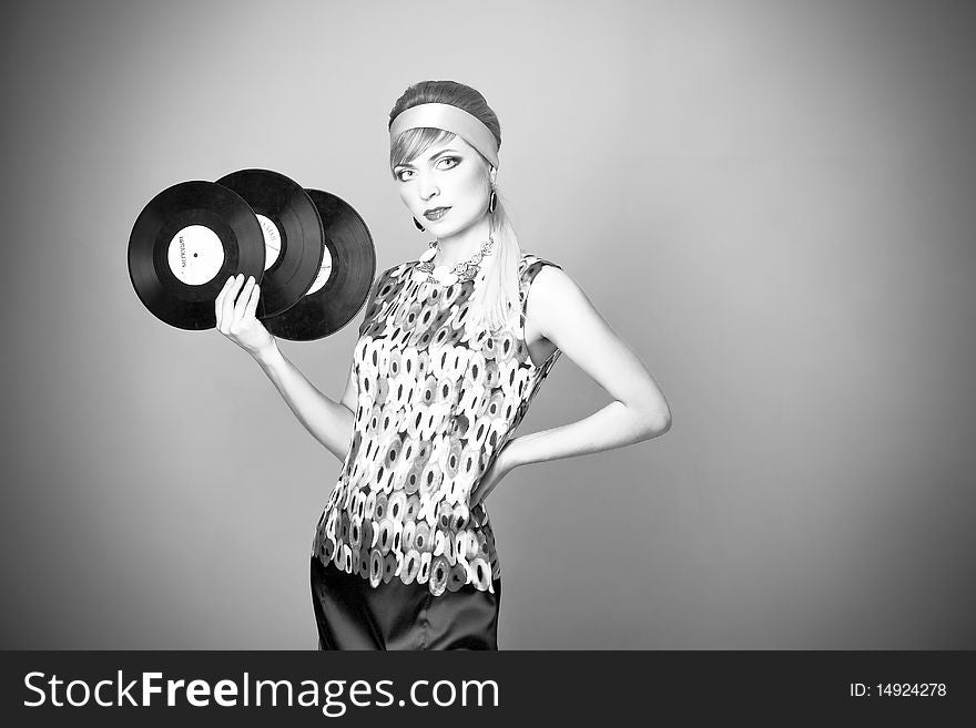 Beautiful fashion girl on the grey background with plates for the gramophone