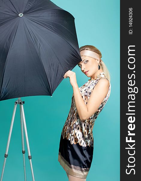 Beautiful fashion girl on the turquoise background with umbrella