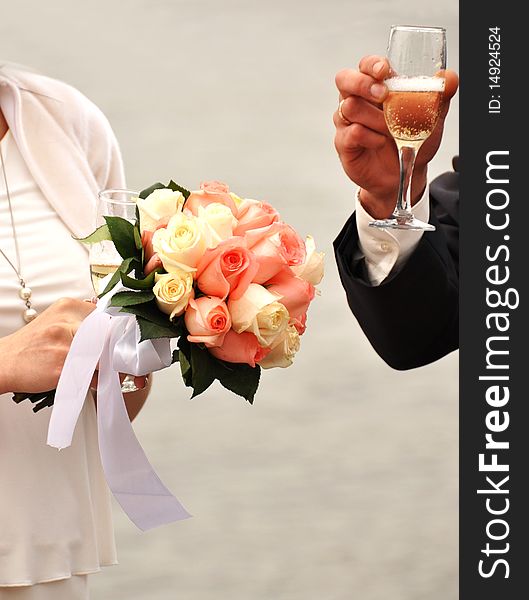 Glass of champagne in a hand of the groom,flower in the hands of the bride. Glass of champagne in a hand of the groom,flower in the hands of the bride