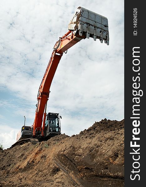 Loader Excavator doing construction works standing in field with risen bucket outdoors. Loader Excavator doing construction works standing in field with risen bucket outdoors