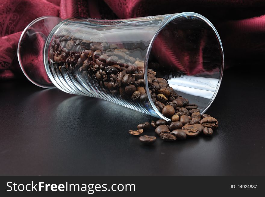 Pure glass with coffee granules on black table with red samet background