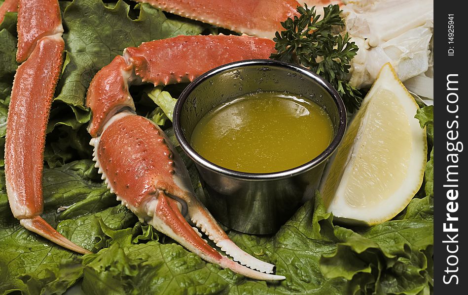 A red crab pinch from a close up view with melted butter on the side in a cup and a slice of fresh lemon. A red crab pinch from a close up view with melted butter on the side in a cup and a slice of fresh lemon.