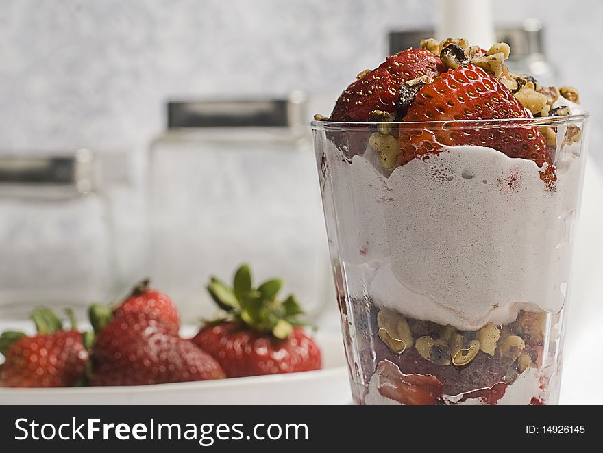 A strawberry glass with some nuts and ice cream. A strawberry glass with some nuts and ice cream