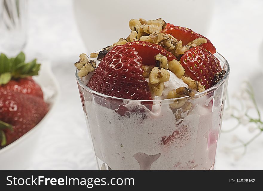 A strawberry glass with some nuts and ice cream viewed from the side. A strawberry glass with some nuts and ice cream viewed from the side.