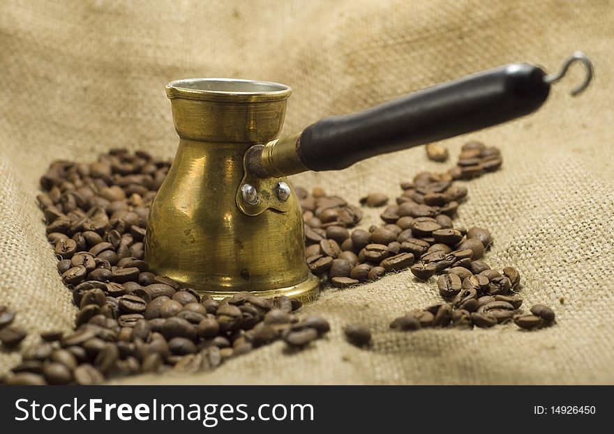 Coffee pot with roasted coffee beans, on linen background