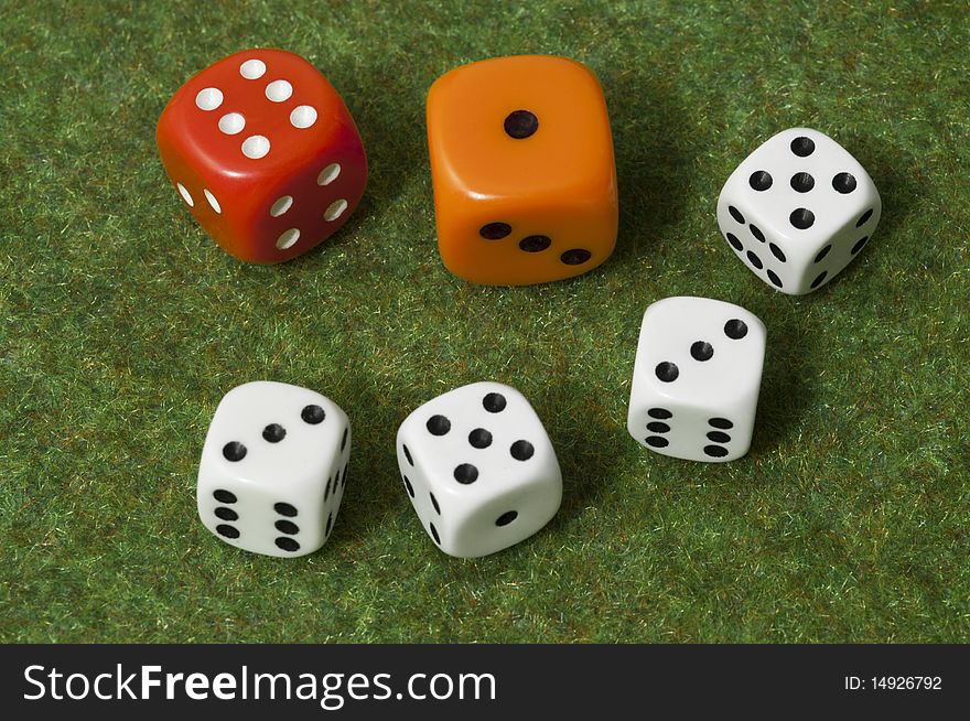 Red die wins orange lose, over four white dice on green floor. Red die wins orange lose, over four white dice on green floor
