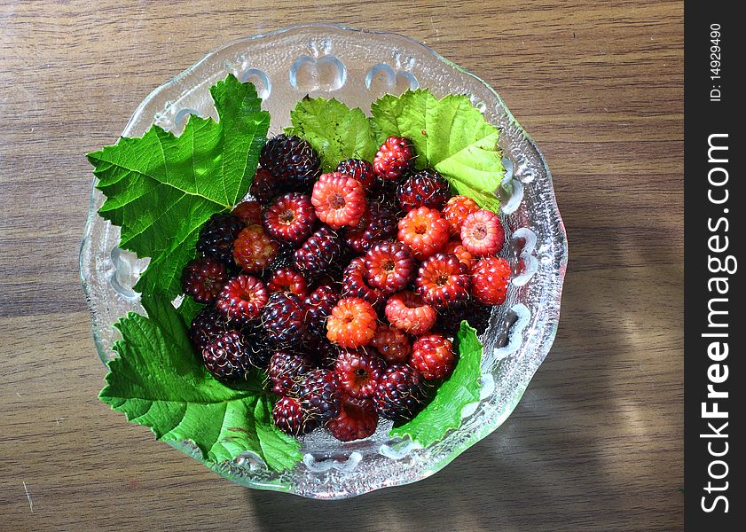 Red and purple raspberries in glass bowl.