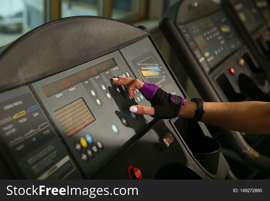 The female hand presses the button on the treadmill. the girl`s finger presses the button. the settings of the treadmill.